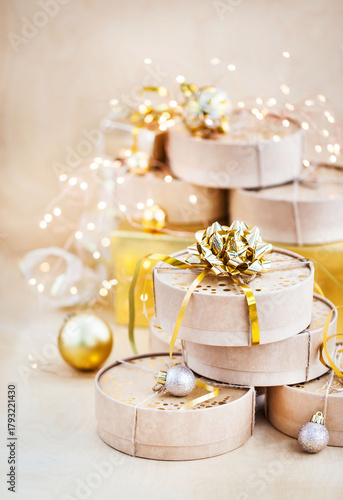Christmas or New year round kraft gift boxes, gold holiday balls on a bokeh background of twinkling party lights of garland