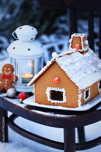 Gingerbread house and holiday decoration on chair in snow winter outdoor background