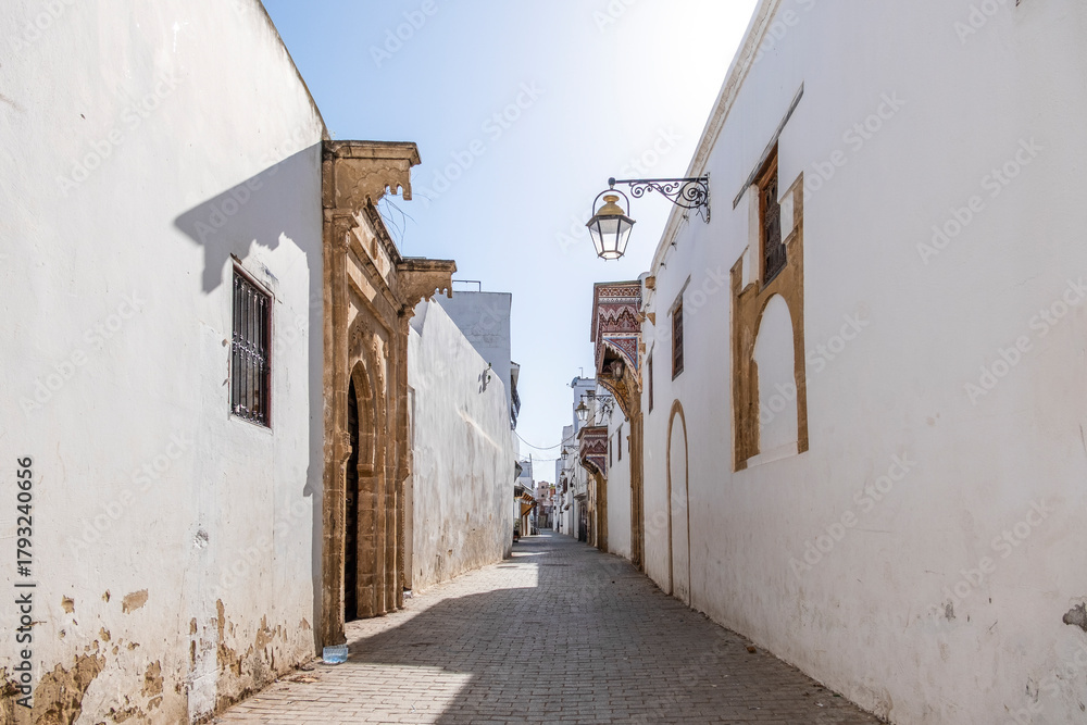 Obraz premium Rabat, Morocco – Traditional Narrow Street in the Medina with Whitewashed Walls and Wooden Doors
