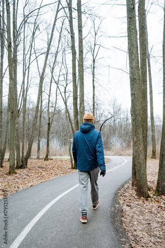 energetic outdoor workout, active man in blue jacket engaging in fitness walk on leafcovered pathway
