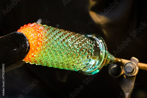 A glass crafter is burning and blowing an art piece.