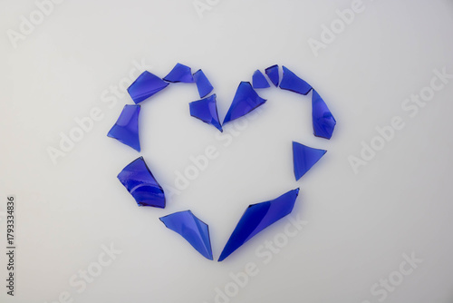A heart made of blue glass shards on a white background. The concept of love and separation.