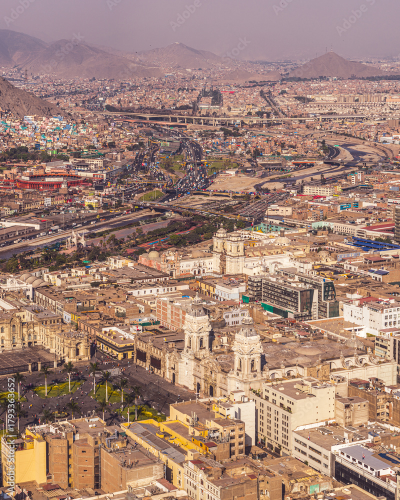 Fototapeta premium High-angle aerial view of Lima's historic center, featuring the Cathedral at Plaza de Armas, San Francisco Church, and the vast Pan-American highway.