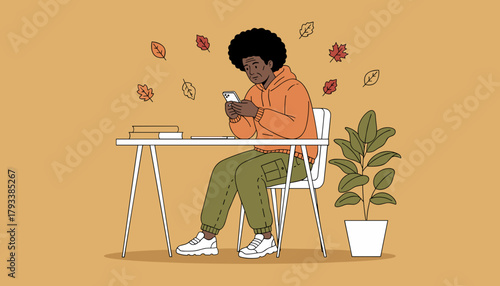 African American man texting on phone at desk in an autumn setting