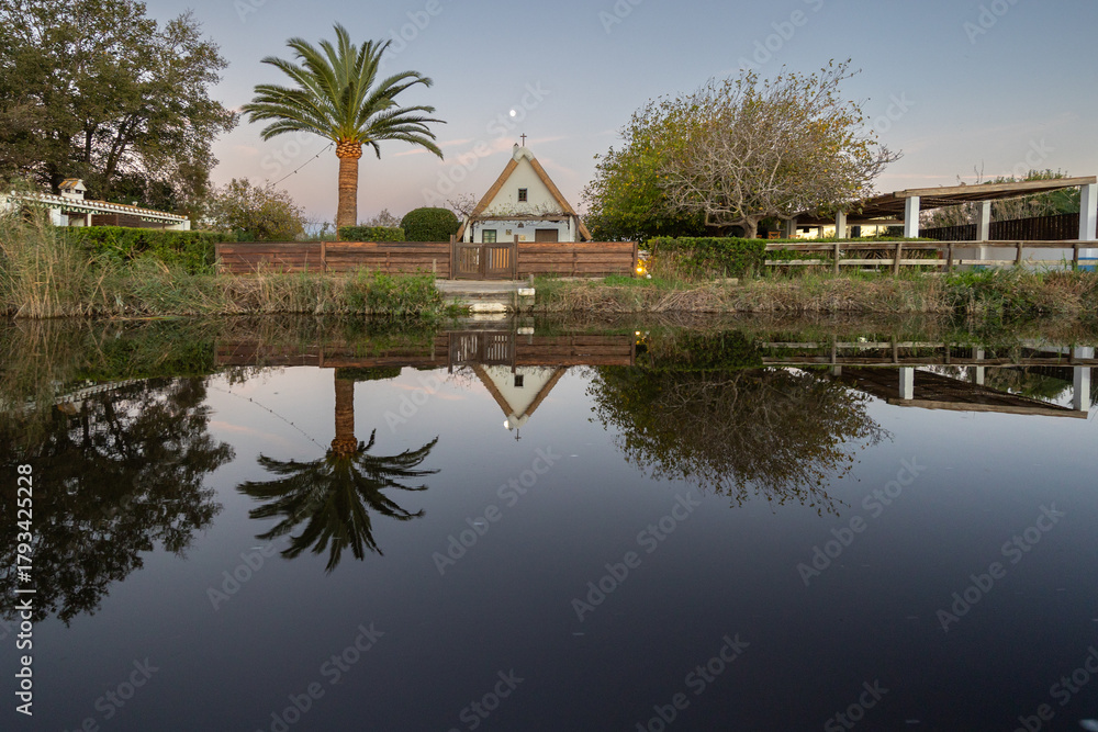 Obraz premium Albufera lake reflecting traditional house and palm tree