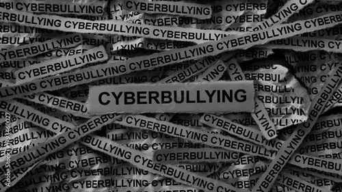 Strips of newspaper with the words Cyberbullying typed on them. Black and white. Close up.