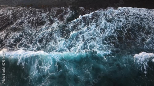 Stunning slow motion footage of powerful blue waves impacting dark rocky coast with spectacular water spray