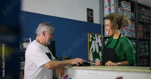 Smiling young woman and older man engaging in a light-hearted exchange during a transaction at a hardware store counter