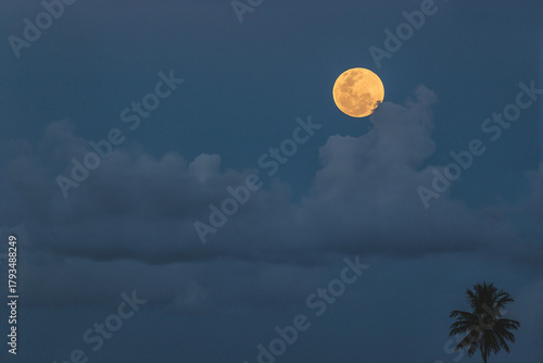 Full moon rising above clouds at dusk