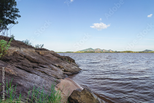 Rocky lakeshore with mountains under clear blue sky