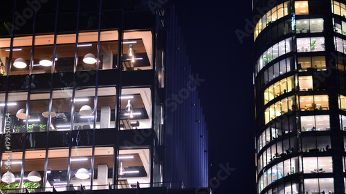 Modern office building in city center illuminated at night. Rows of lit windows against the architectural grid of a modern facade.