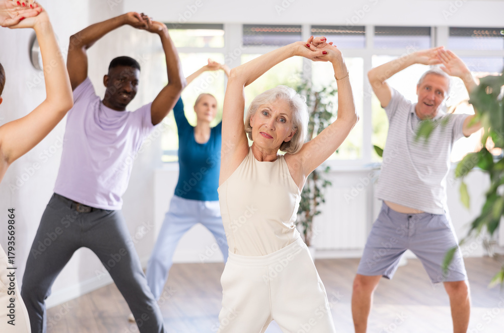 Naklejka premium Active mature men and women practicing Jazz-funk dance in training hall during dancing classes