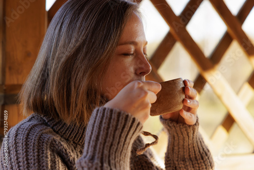 Enjoying a warm drink while relaxing in a cozy wooden cabin with a beautiful view outside
