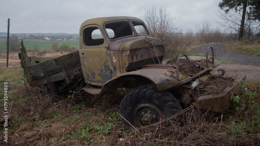 Fototapeta premium rusty truck with missing parts and weeds, deteriorated pickup surrounded by nature and neglected elements