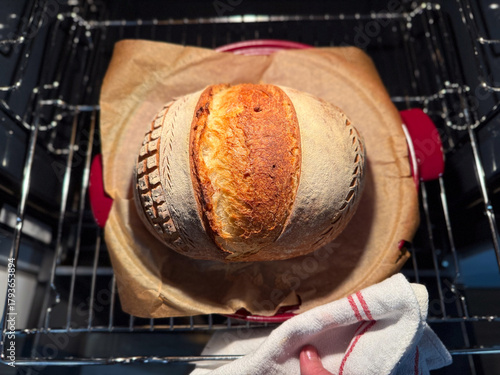 homemade bread emerges from oven, warm kitchen glow highlights freshly baked loaf resting on lined tray