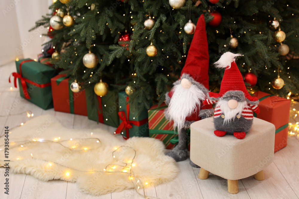 Naklejka premium Funny gnomes near Christmas tree and gift boxes in decorated room, space for text