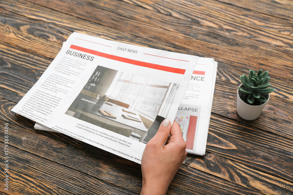 Naklejka premium Woman reading newspaper on wooden background