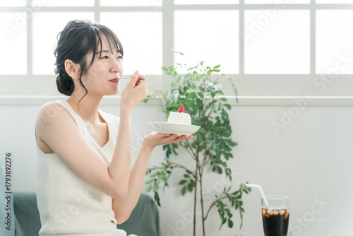 Obraz na plátně A woman eating a cake as a snack at home