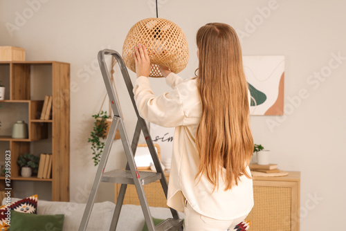 Young woman screwing light ...