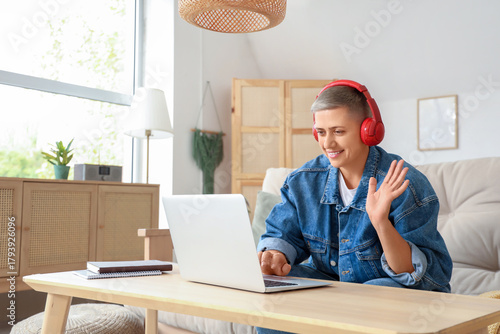 Remote work and video call communication, woman with headphones waving hello ...