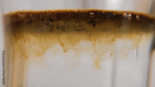 Instant coffee granules falling into hot water and dissolving with spoon stirring, macro shot. Morning routine concept