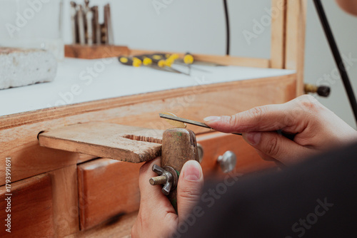 Canvas Print Jeweler artisan hands filing metal with hand file on wooden bench pin in jewelry