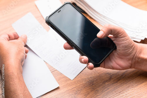 Hand using smartphone to scan and photograph receipts for budgeting, expense tracking, and tax deduction