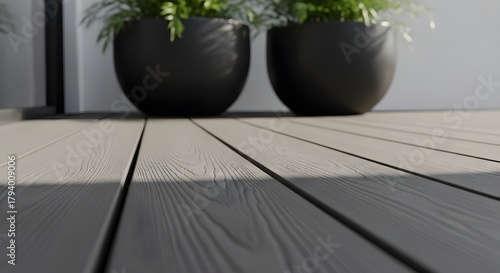 Close up of a modern composite deck with two dark planters holding lush green plants in soft natural light