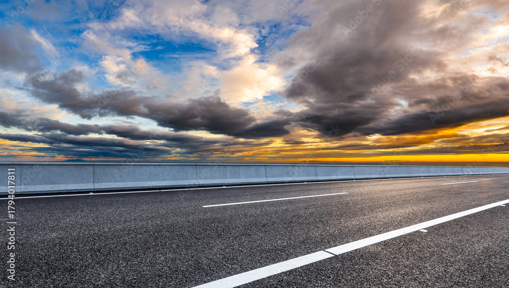 Fototapeta premium Empty asphalt road and dramatic sky clouds at sunset