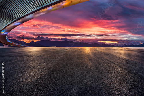 Fototapeta Naklejka Na Ścianę i Meble -  Asphalt road and bridge with dramatic sky clouds at sunset