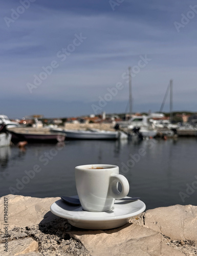Fototapeta Naklejka Na Ścianę i Meble -  cup of coffee by the sea at the beach with boats in the port in Croatia