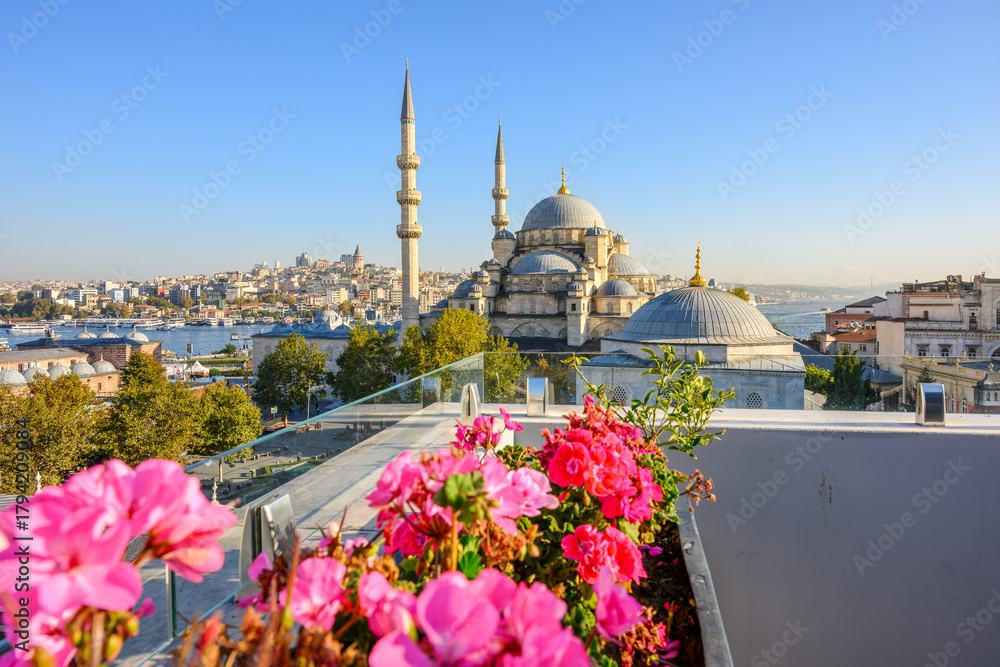 Fototapeta premium The New Yeni Mosque rises above the Eminonu district with the Bosphorus Strait and Galata Tower in view in the distance in Istanbul, Turkey.