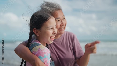 An happy elderly woman grandmother and a young girl loving hugging together on the beach together. Leisure enjoying the weekend concept