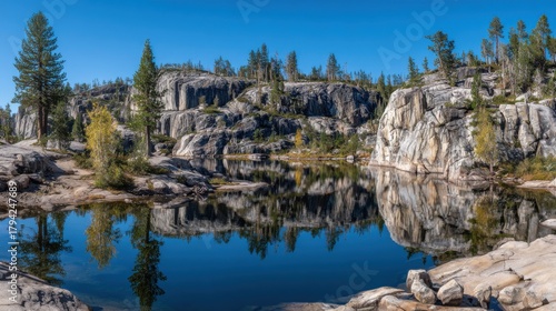 Serene Rocky Landscape with Reflective Water and Lush Greenery Under Clear Blue Sky in a Tranquil Natural Environment