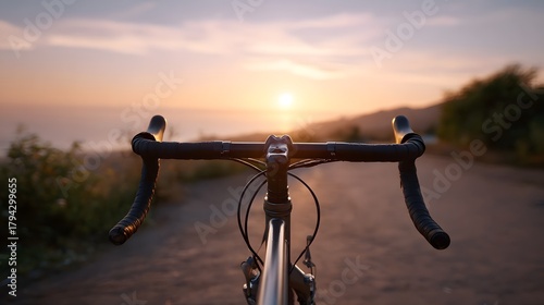 View from a bicycle handlebar looking out at a beautiful coastal sunset over the ocean with warm light illuminating the scene