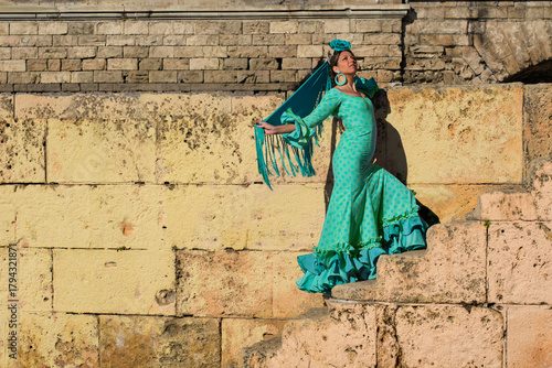 the beautiful girl in the flamenco dress dances on the stairs