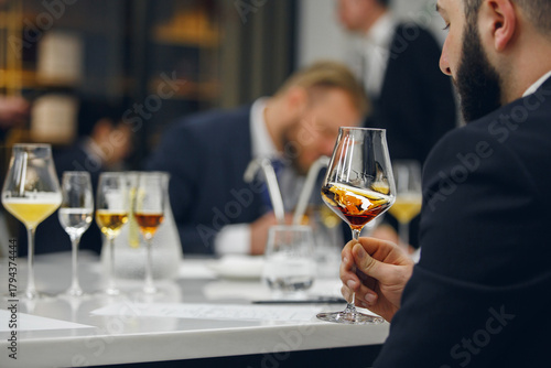 Sommelier looking at color of drink during alcohol beverages training. Training of restaurant staff, studying alcohol list.