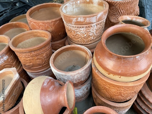 Stacked clay terracotta planters with decorative relief details sit nestled together for high resolution photo