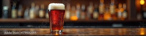 A pint of dark amber brewery bitter, head forming, served in a traditional glass on a dark wooden bar top ,  craft,  hoppy,  aromatic