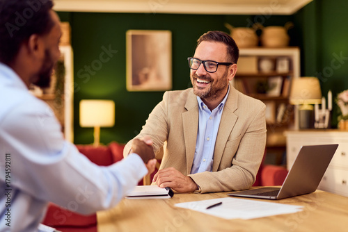 Professional Man Shaking Hands Across Table After Successful Business Meeting With Laptop
