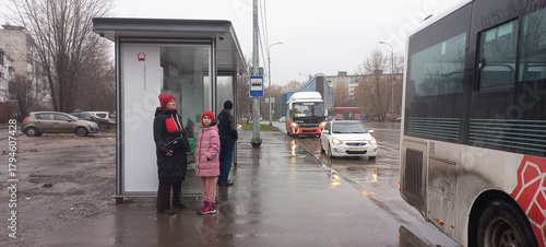 Adults and child waiting at bus stop on rainy day in city  