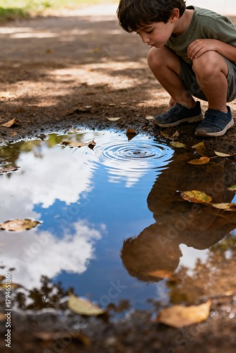 Wallpaper Mural Curious Child Crouching by Puddle Watching Sky and Leaves Reflected in Water Torontodigital.ca