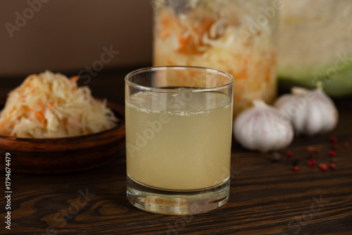 Photography Fresh homemade sauerkraut juice or brine with sauerkraut salad in a plate and jar on a wooden table