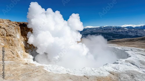 Geyser steam eruption from rocky geothermal crater with rising steam plume under clear blue sky
