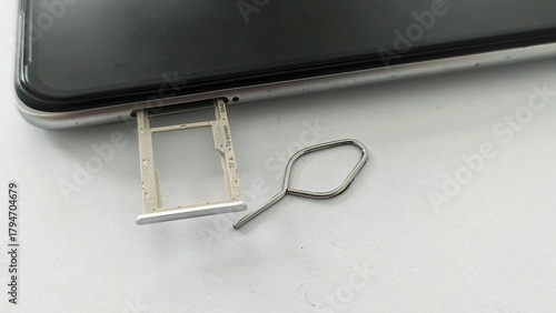 Canvas Print Top corner close-up of a mobile phone with a metallic ejector pin used to partially open the SIM card tray