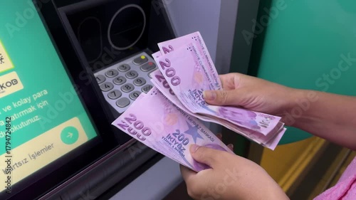 Woman counting 200-lira banknotes at ATM illustrating rapid Turkish inflation