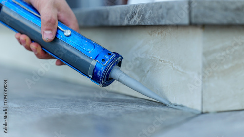 Applying sealant with a caulking gun to seal a gap between tiles © shine.graphics