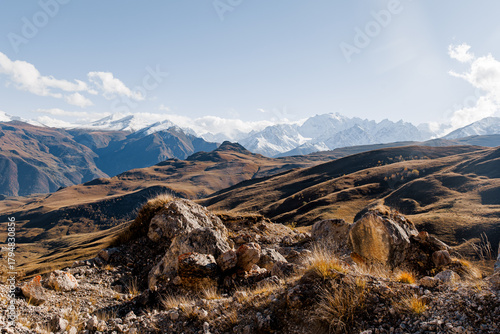 Snow-capped mountains in Kabardino-Balkaria under a cloudy sky. The landscape features rugged peaks and valleys, showcasing the natural beauty of the region.