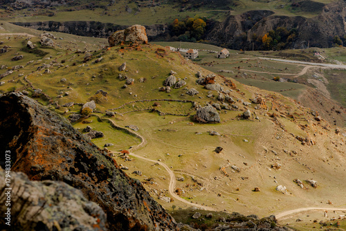 Scenic view of rocky hills and a winding path. The landscape features sparse vegetation and rugged terrain under a clear sky.