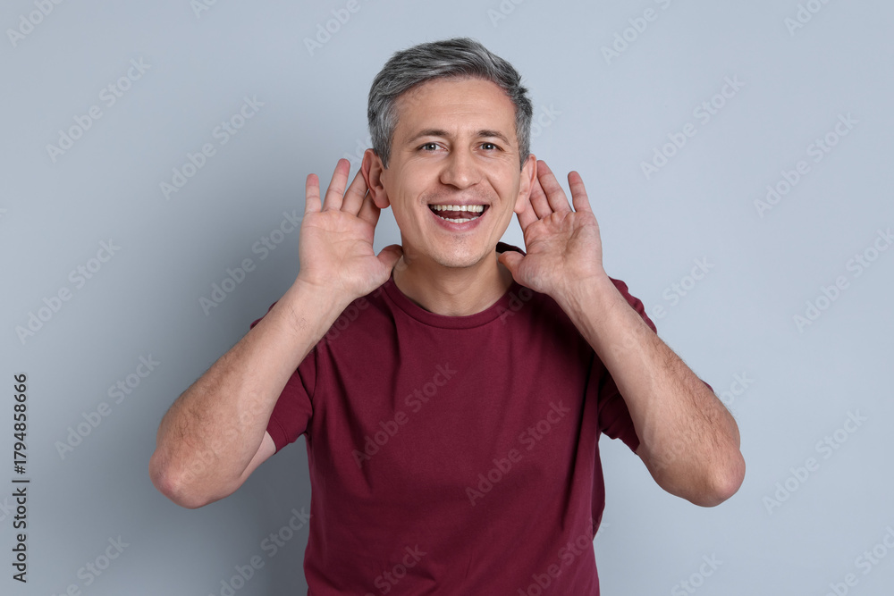 Naklejka premium Man showing hand to ear gesture on light grey background